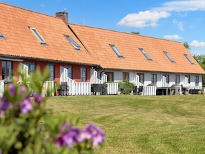 A row of single-story buildings with red-tiled roofs and multiple windows. - 4 Person Holiday Park Home in Gudhjem (Gudhjem)
