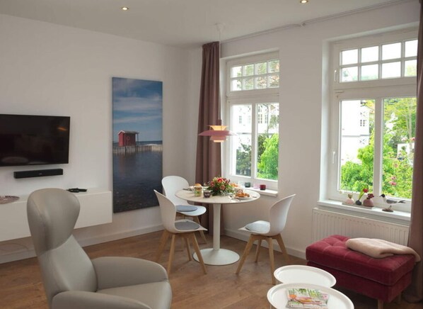 Ein modernes Hotelzimmer mit Essbereich, Fernseher und großen Fenstern mit Blick ins Freie.