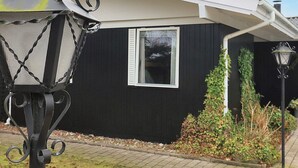 A black house with a window, a lamp post, and a small garden area. - 4 Star Holiday Home in Vaeggerlose (Vaeggerlose)