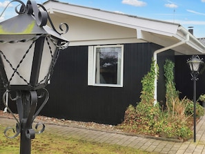 A black house with a window, a lamp post, and a small garden area. - 4 Star Holiday Home in Vaeggerlose (Vaeggerlose)