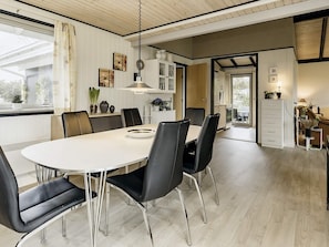 Un espace de salle à manger moderne avec une table ronde, des chaises noires et un luminaire suspendu.