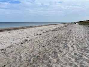 Une plage de sable avec un véhicule garé sur le côté droit.