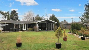 A residential property with a covered patio, a lawn, and potted plants. - 4 Star Holiday Home in Vaeggerlose (Vaeggerlose)