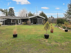 A residential property with a covered patio, a lawn, and potted plants. - 4 Star Holiday Home in Vaeggerlose (Vaeggerlose)