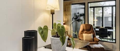 A modern living room with a white console table, a potted plant, a lamp, and a leather armchair.
