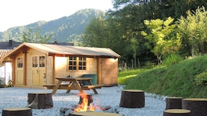 A wooden cabin with a fire pit and picnic table in a gravel area. - Holiday Apartment at the Rose Garden (Fuessen)