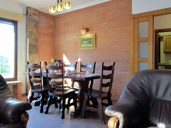 Una zona de menjador amb paret de maó, taula i cadires de fusta.