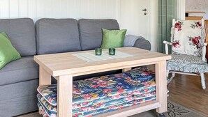 Una sala de estar con un sofá gris, una mesa de centro de madera y un sillón estampado.