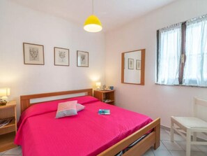 A bedroom with a bed, bedside tables, a chair, and artwork on the walls. - Seaside Villa Retreat in Stintino (Stintino)
