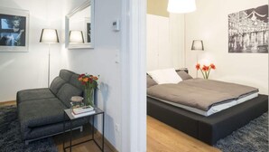 Moderni makuuhuone, jossa on sänky, yöpöydät, peili ja seinään kiinnitetty valaisin.