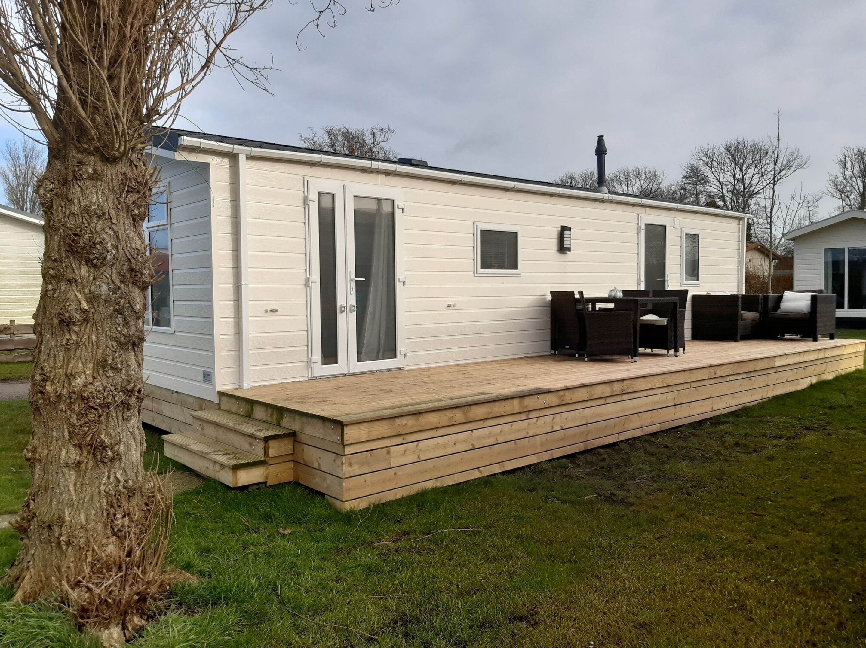 A mobile home with a deck, a dining area, and a large window.