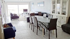 A spacious living area with a dining table, sofas, and a cabinet with glass doors. - Apartment in Nieuwpoort by the Beach (Nieuwpoort)