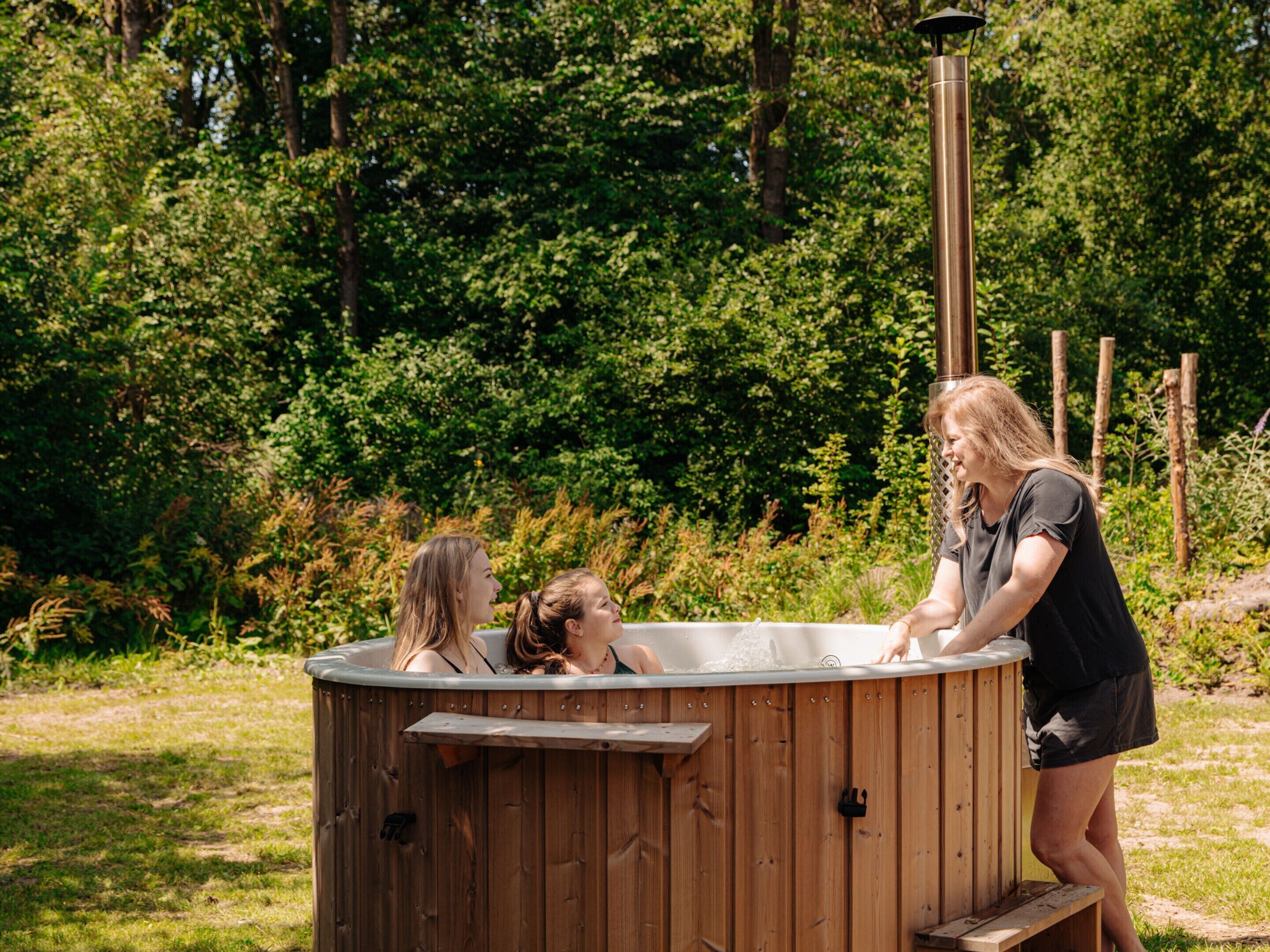 Un bain à remous en bois, avec un poteau en métal et un banc.