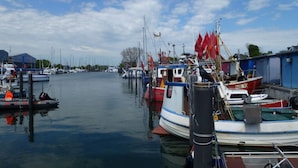 A marina with several boats docked, a clear sky, and calm water. - Deck 2 Modern Retreat (Timmendorfer Strand)