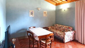 A dining area with a table and chairs, a floral sofa, and a ceiling with exposed beams. - Spacious Apartment With Bubble Bath (Monteverdi Marittimo)