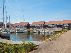 Un port de plaisance avec des bateaux amarrés, une jetée en bois et une rangée de maisons aux toits rouges.