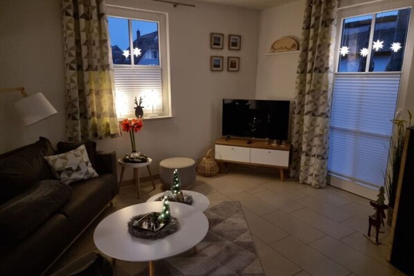 Un salon comprenant un canapé, une table basse, un téléviseur et des objets de décoration.