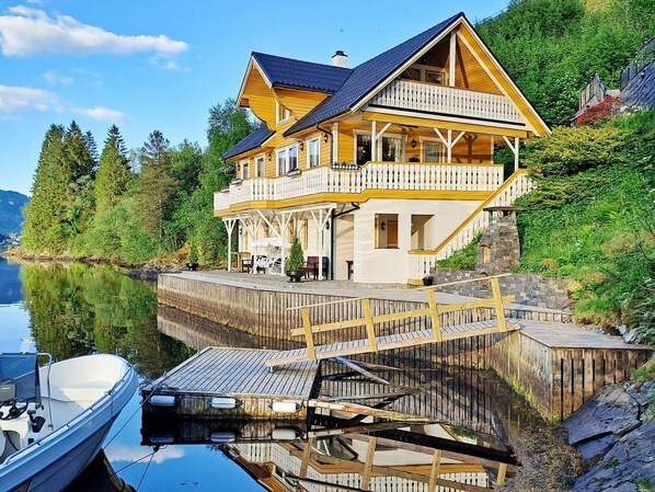 A large wooden house with a balcony, a dock, and a boat. - 8 Person Holiday Home in Bygstad (Sunnfjord)
