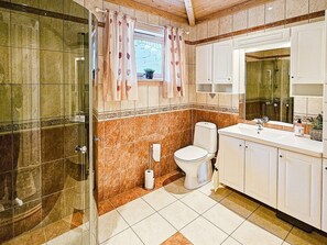 A bathroom with a shower, toilet, sink, and a window with curtains. - 8 Person Holiday Home in Bygstad (Sunnfjord)