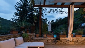 An outdoor patio with a stone wall, a wooden pergola, a sofa, and potted plants. - Charming Apartment in Rasa-labin (Rasa)