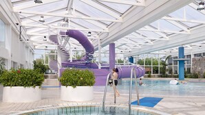 An indoor swimming pool with a slide and a water feature.