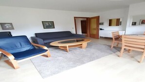 A living room with a sofa, a coffee table, a dining table with chairs, and a door leading to another room. - House Fischergasse (Titisee-Neustadt)