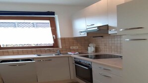 A compact kitchen with a sink, stove, and cabinets. - House Fischergasse (Titisee-Neustadt)