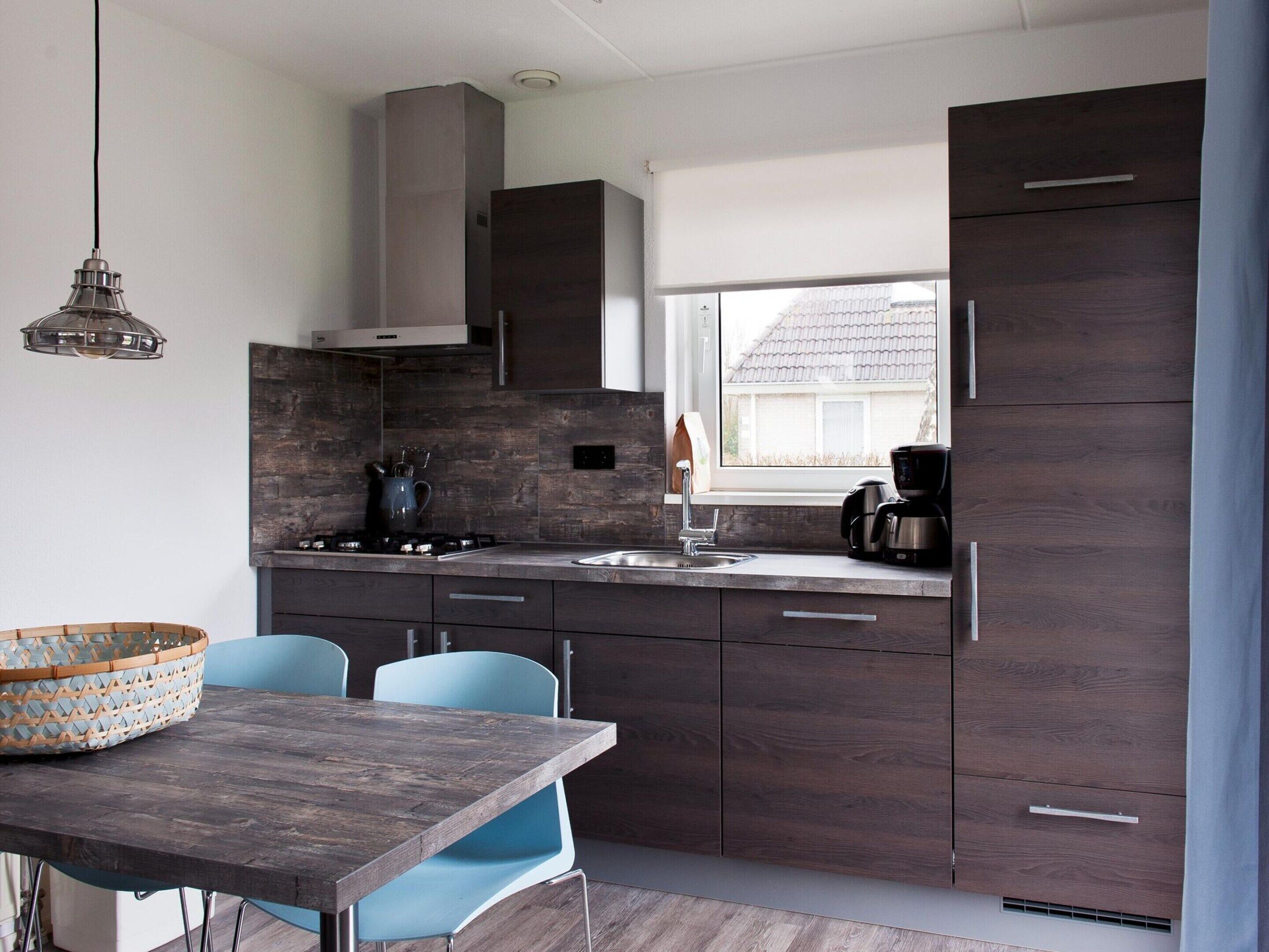 Une cuisine moderne avec des meubles de couleur bois foncé, une cuisinière à gaz et une machine à café.