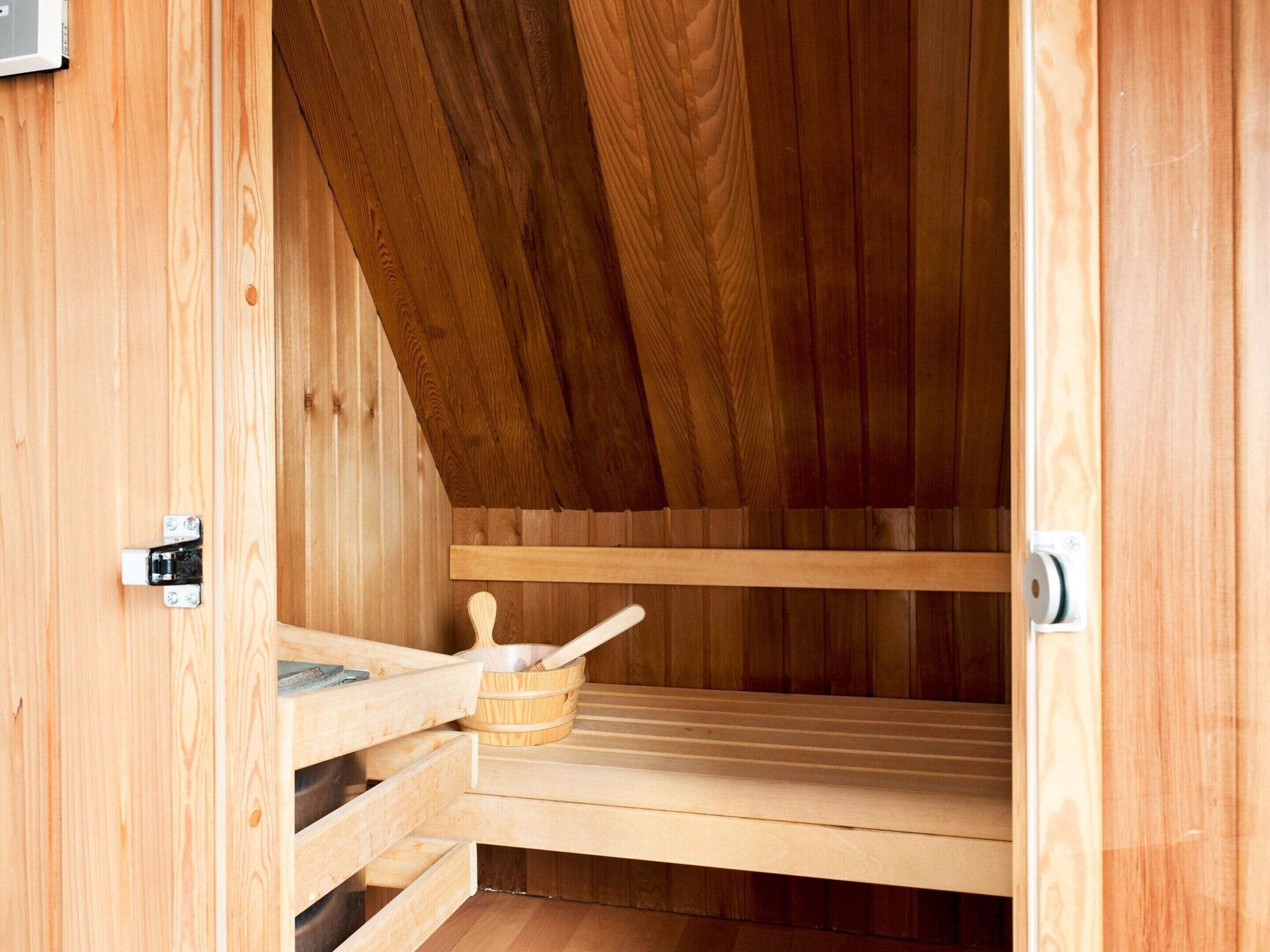 Eine Holzsauna mit Bänken und einem Holzeimer.