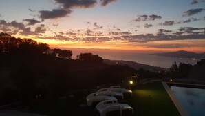 A sunset view from a hotel balcony with a pool and lounge chairs. - Between sea and mountains (porticcio)