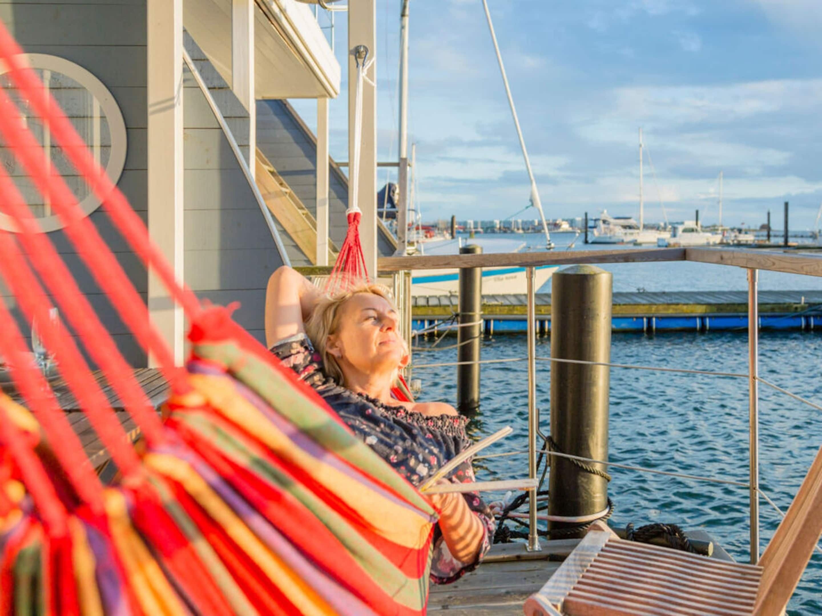 Iemand ontspant op een dek met uitzicht op de jachthaven en boten.