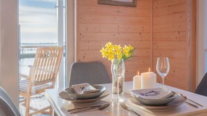 Et spisebord dækket med tallerkener, bestik, en vase med gule blomster og stearinlys.