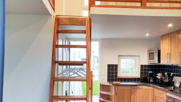 A modern kitchen with wooden cabinets, a built-in microwave, and a black tiled backsplash.
