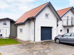 A modern two-story residential building with a red-tiled roof, a garage, and a paved driveway. - 4 Person Holiday Home in Glommen (Glommen)