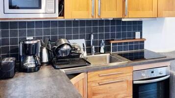 Una cocina equipada con microondas, cafetera, tostadora, lavabo y horno.