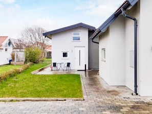 A modern house with a white exterior, a small patio with two chairs, and a brick pathway leading to the entrance. - 4 Person Holiday Home in Glommen (Glommen)