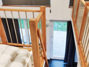 A room with a bed, a wooden railing, a door leading outside, and a view of a brick patio. - 4 Person Holiday Home in Glommen (Glommen)