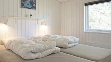 Una habitación con cama, ventana y estante con lámpara.