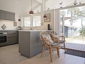 Una cocina moderna con una isla grande, sillas de madera e iluminación colgante.