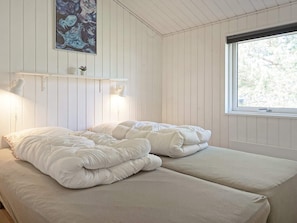 A bedroom with a bed, a window, and a wall-mounted shelf with a lamp. - 5 Star Holiday Home in Nexo (Nexø)
