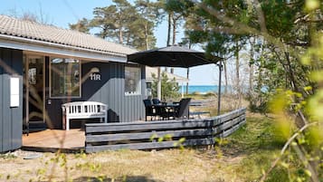 Una propiedad costera con patio cubierto, mobiliario exterior y vista al mar.