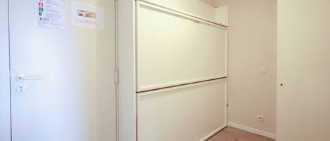 Una habitación con una puerta blanca, un armario blanco y suelo de madera.