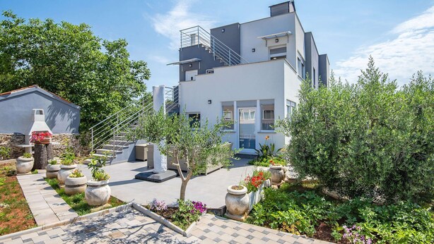 A modern two-story building with a covered outdoor area, stone planters, and a paved walkway. - Apartment in Croatia Near Stunning Coastline (Medulin)