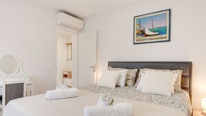 A bedroom with a bed, a bedside table with a lamp, a mirror, and a painting of a boat on the wall. - Apartment in Croatia Near Stunning Coastline (Medulin)