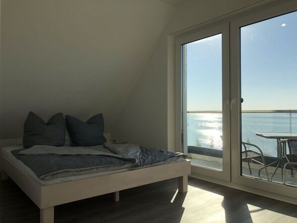 A bedroom with a bed, pillows, and a view of the sea through a large window. - Holiday Home Yuna Comfortable Vacation Home (Alt Schwerin)
