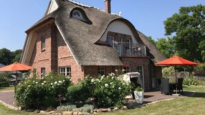 A house with a unique sloped roof, brick exterior, and a balcony with a railing. - Holiday Home Rugen-dream (Poseritz)