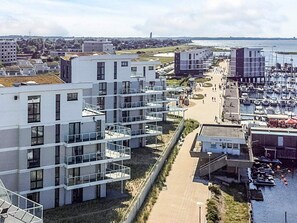 A modern residential area with multi-story buildings, a marina with boats, and a clear view of the sea.