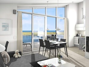A modern hotel room with a large sliding glass door leading to a balcony with a view of the sea.