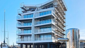 A multi-story building with a modern architectural design, located over a body of water. - Holiday Home in Wendtorf (Wendtorf)