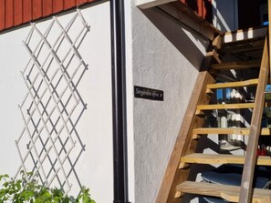 A wooden ladder leading to a lofted area with a metal grid structure on the wall and a sign reading "Sorgarden övre". - 7 Person Holiday Home in Grisslehamn (Grisslehamn)